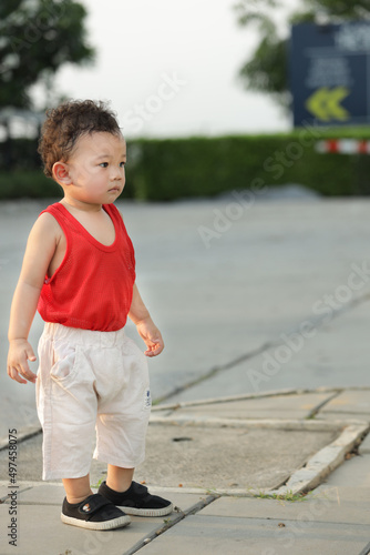 boy in red shirt and white pants standing
