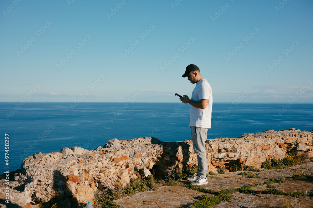 Young man operating a drone over the sea