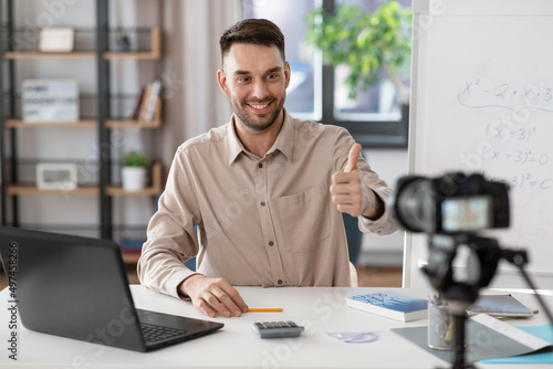 distance education, school and remote job concept - happy smiling male math teacher with camera having online class and showing thumbs up at home office