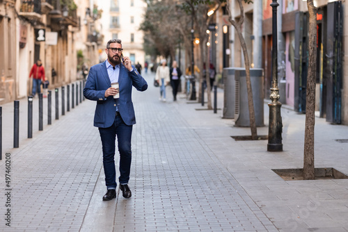 Businessman walking through center of Barcelona talking on phone