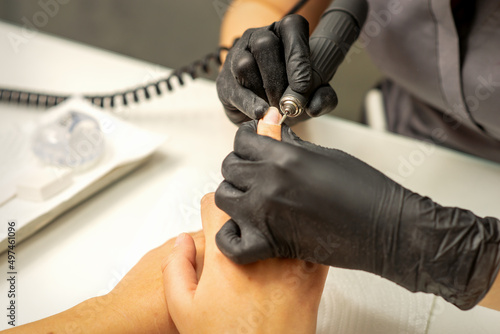 Manicure master uses electric nail file machine in a nail salon, close up © okskukuruza