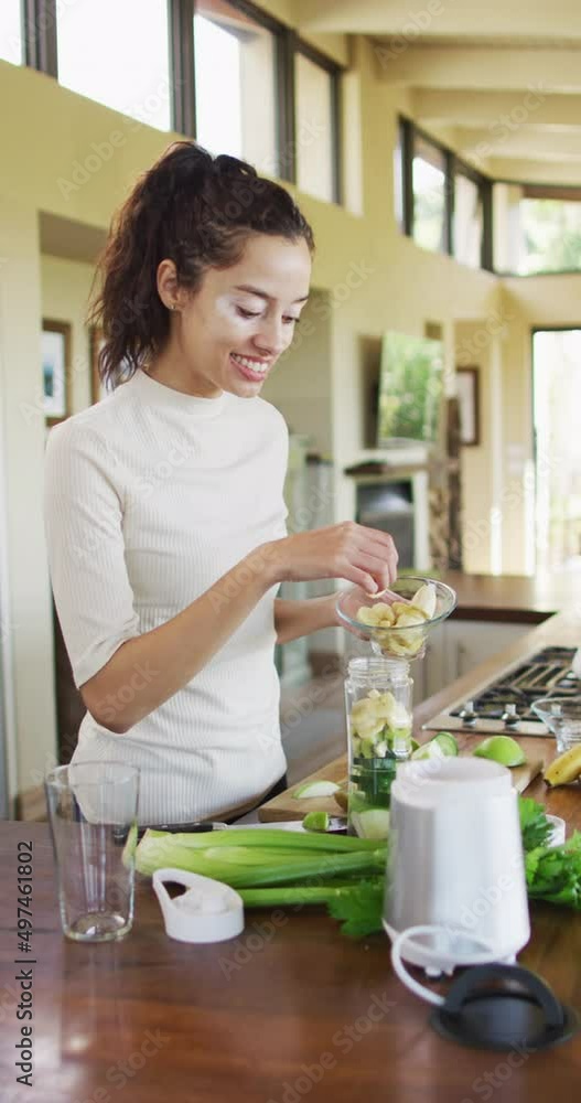 Vertical video of smiling biracial woman with vitiligo making health drink in kitchen Vertical video of smiling biracial woman with vitiligo making health drink in kitchen
