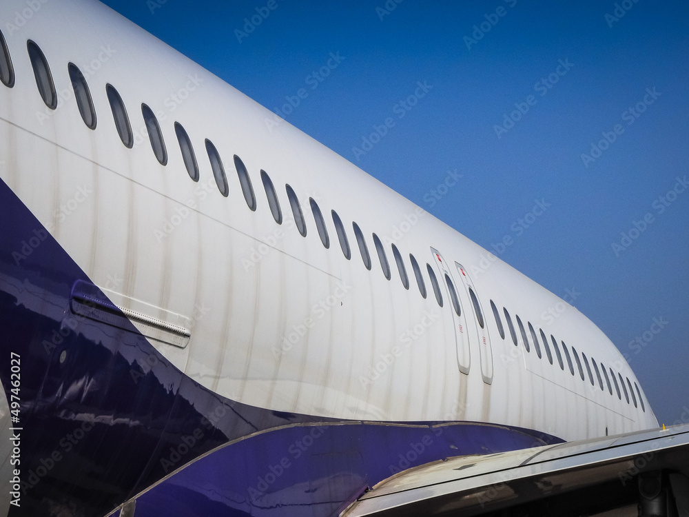 Fuselage of airplane with door and windows. Row of portholes outside the passenger aircraft. Plane on bly sky background.
