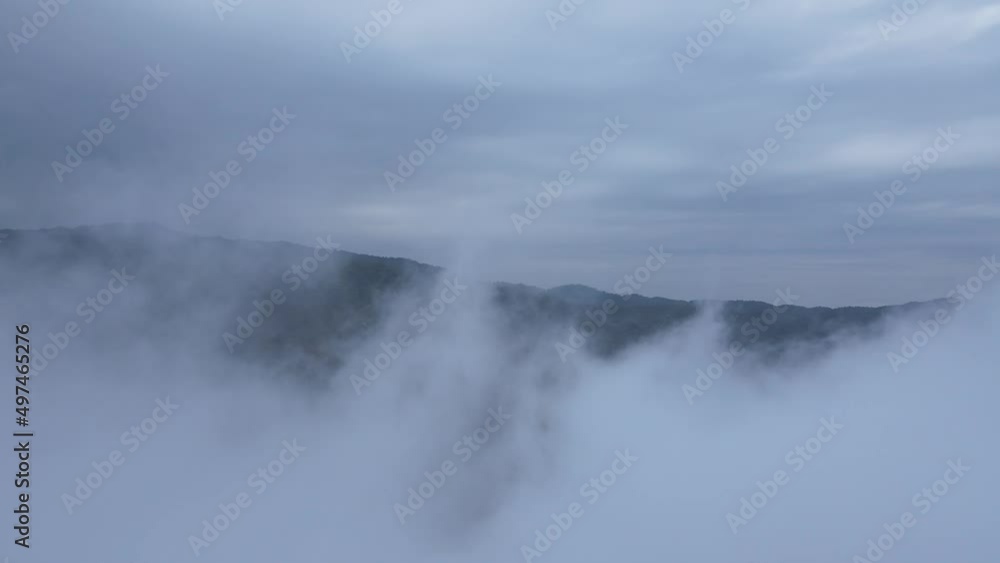 Mystical clouds and fog descending on hillside during sunrise aerial drone shot Mystical clouds and fog descending on hillside during sunrise aerial drone shot