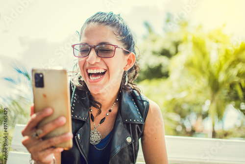 Close up of a happy girl checking her cell phone, Happy woman sitting with her cell phone outside, cell phone, Happy woman sitting on a bench sending a text message