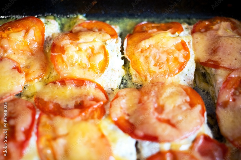 A dish of red salmon fish cooked in a large pan with tomatoes and cheese and emits mouth-watering aromas A dish of red salmon fish cooked in a large pan with tomatoes and cheese and emits mouth-watering aromas