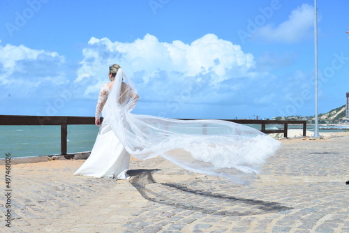 bride in dress on beach, bride with her back and veil flying
