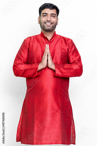 A portrait of a indian man in a traditional wear in welcome gesture pose - Namaste. photo