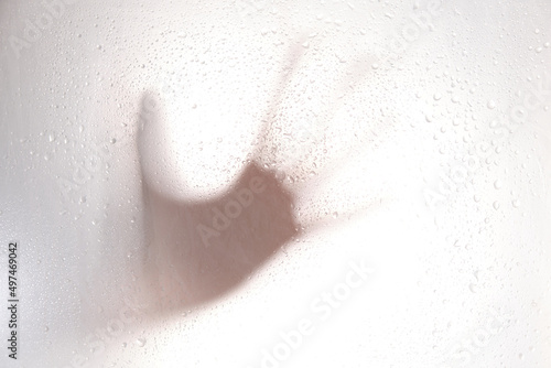 blurred silhouette hand. Grey shadows of one reaching hand on the wall. Abstract blurred effect frosted glass illuminated from behind.