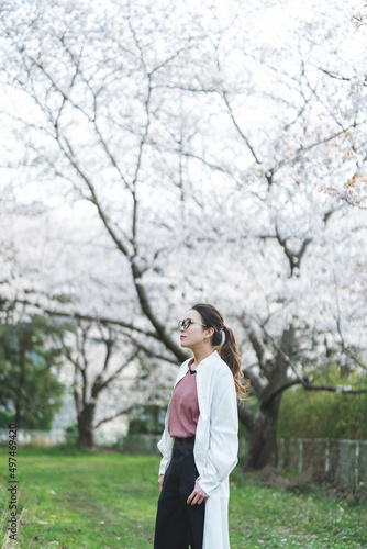 桜の花を見る眼鏡をかけた女性
