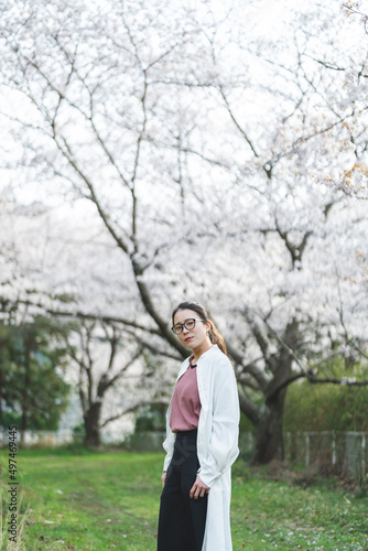 桜の花を見る眼鏡をかけた女性