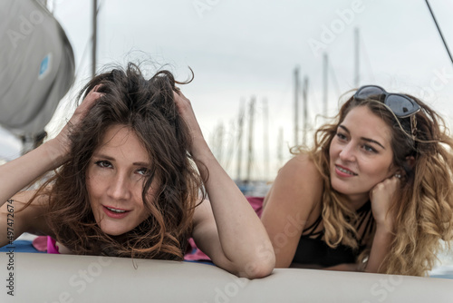 young, beautiful and happy girl friends laying together on a sail boat