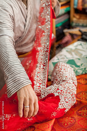 hand holding a Red and silver lace fabric 