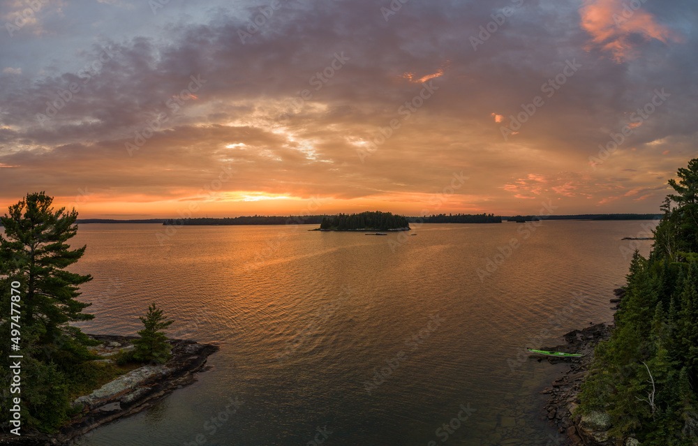 A kayak stopped at an island campsite during a fiery summer sunset at Eagle Lake, Northwest Ontario, Canada.