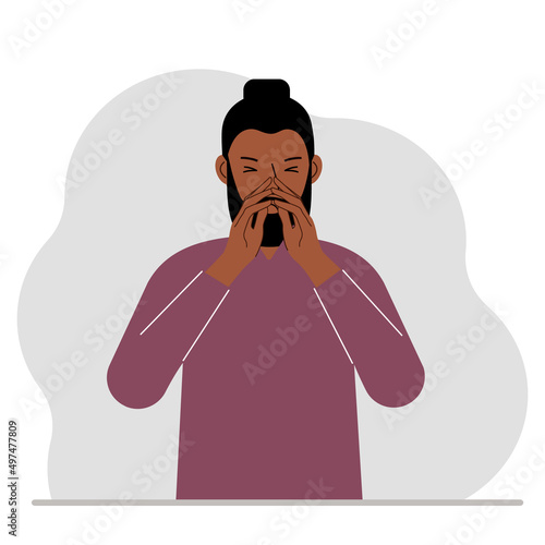The man covers his nose with his hands. The concept of a sick person, sneezes, seasonal allergies, bad smell.