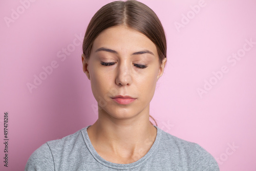 Portrait of a woman with closed eyes on a pink background