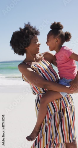 Vertical video of happy african american mother with daughter at beach