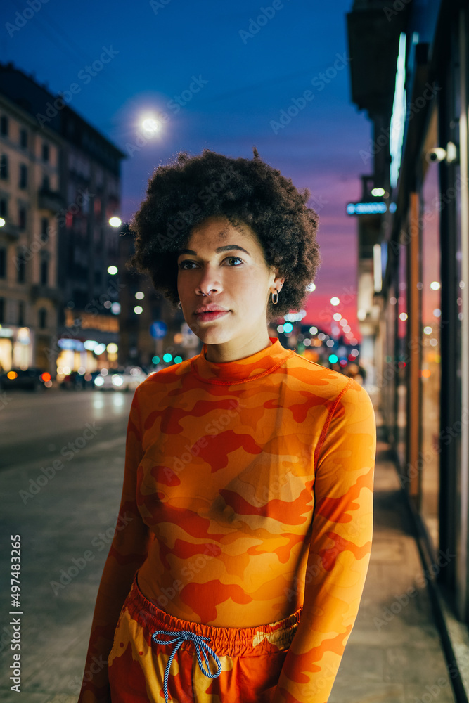 Fototapeta premium Young black woman curly hair stylish fashionable posing outdoor looking camera cool attitude