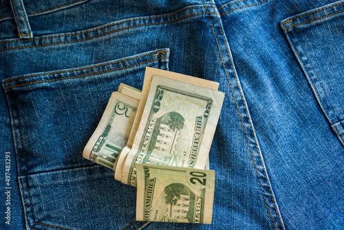 Money is scattered on blue jeans.