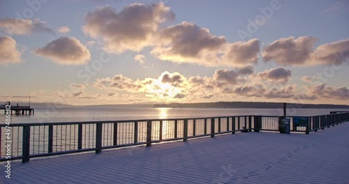 Snowy pier overlooking the water as the sun rises photo