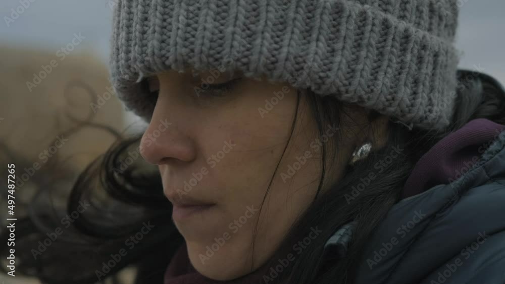 Close up shot on a contemplative woman’s face warming up while enjoying coffee outdoor on a windy and cloudy winter day Close up shot on a contemplative woman’s face warming up while enjoying coffee outdoor on a windy and cloudy winter day