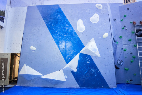 Bouldering climbing problem slab route made on a grey and blue wall with white holds. Ledges, bulges, slopers and crimps photo