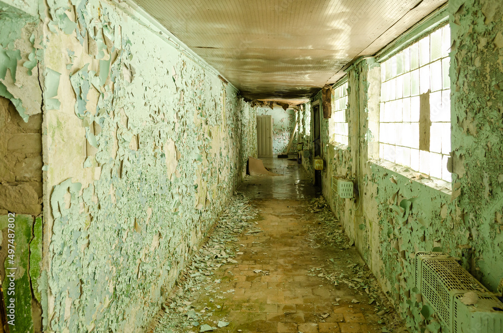 Old, scary hallway with green cracked paint, radiators and windows. Forgotten, abandoned ghost town Skrunda, Latvia. Former Soviet army radar station.