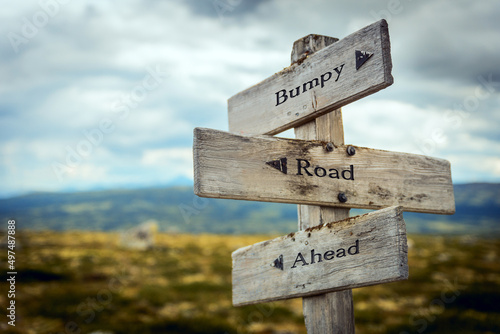 bumpy road ahead text quote written in wooden signpost outdoors in nature. Moody theme feeling.