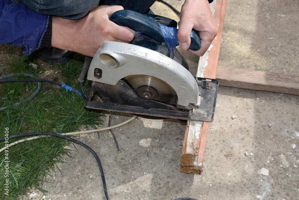 A man works with a circular saw with a wooden frame.