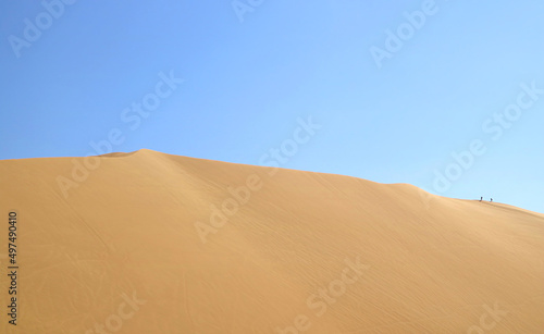 Massive sand dune of Huacachina desert with people walking on the top, Ica region of Peru, South America