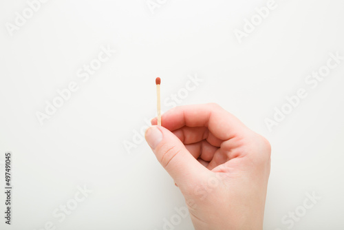 Young adult woman fingers holding match stick on white background. Closeup. Top down view.