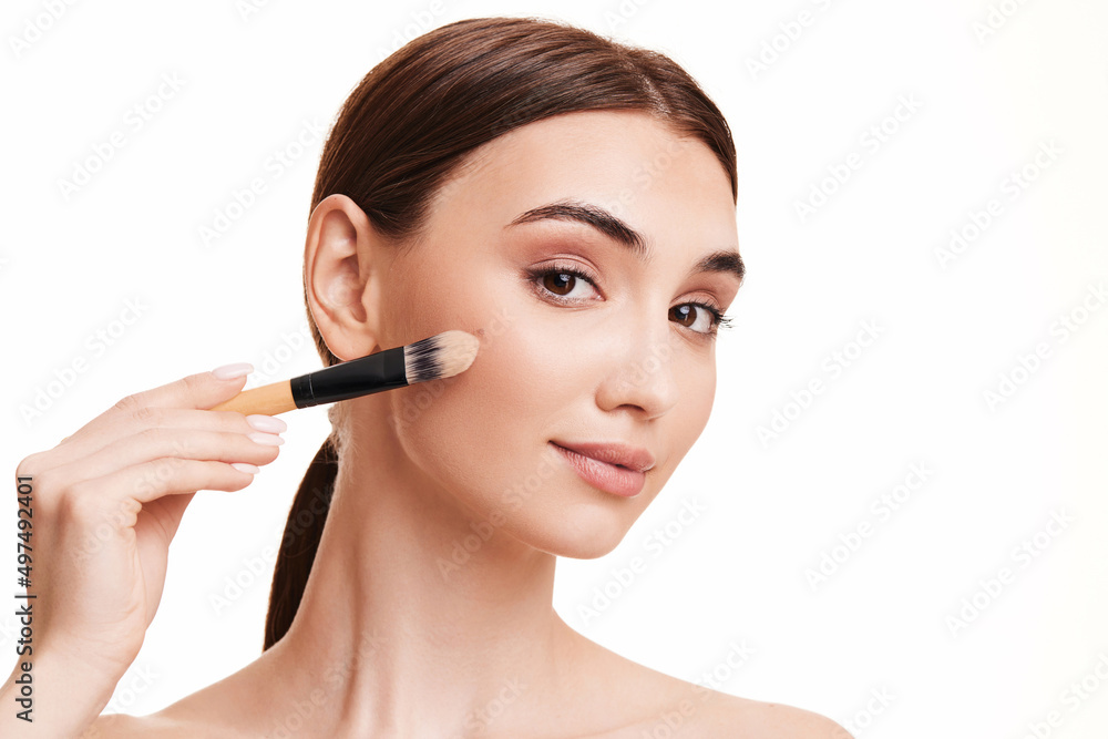 woman applying foundation on skin with makeup brush