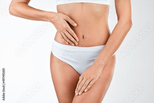 Maintaining a healthy gut microbiome. Shot of a woman touching her stomach against a studio background. © Micah C/peopleimages.com