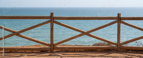 Sea views from a wooden balcony. Viewpoint with wooden fence. Ocean coast and fence at Benagil, Portugal
