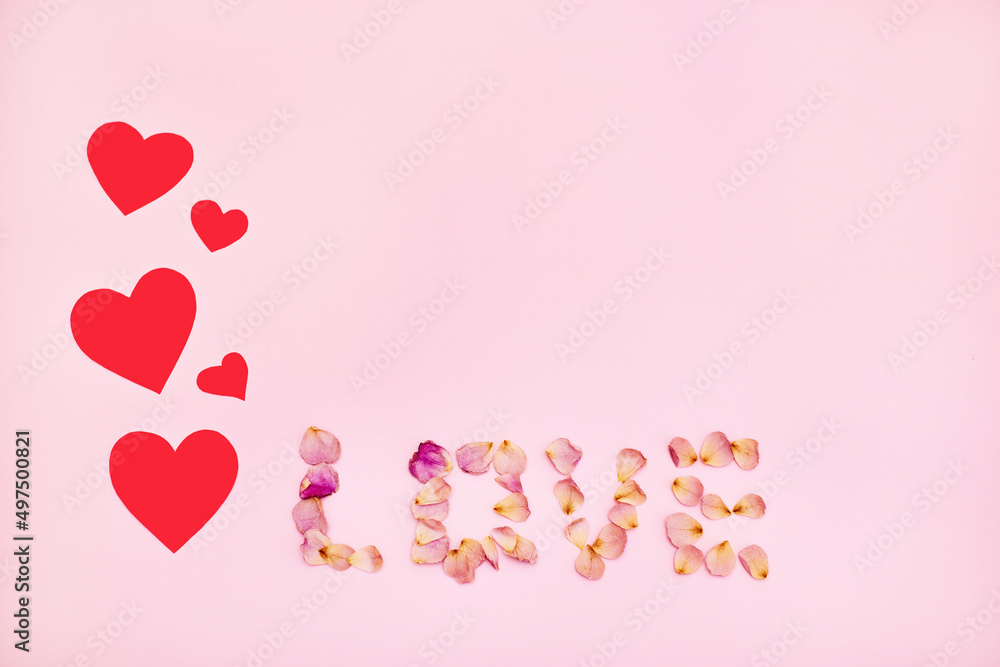 Word love made of pink rose petals on pink background.