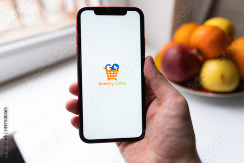 Smart phone with grocery shopping online on screen over blur kitchen background, retail business and technology concept
