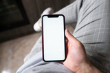 Young man hands holding mobile smart phone with mockup white blank display, empty screen at home. Shopping, delivery apps, social media applications ads,  close up view.