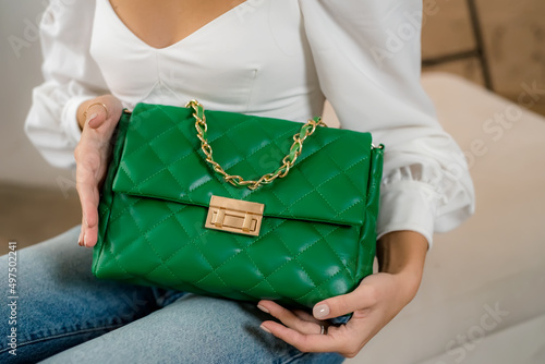 Stylish women's green handbag. Trendy outfit woman with green bag. Girl with bag over his shoulder outdoors. Shoulder Bags for Women. Fashion look woman outfit. Close-up.