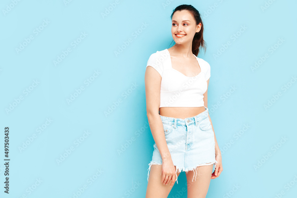Young beautiful smiling female in trendy summer jeans skirt and top clothes. Sexy carefree woman posing near blue wall in studio. Positive brunette model having fun.Cheerful and happy Young beautiful smiling female in trendy summer jeans skirt and top clothes. Sexy carefree woman posing near blue wall in studio. Positive brunette model having fun.Cheerful and happy
