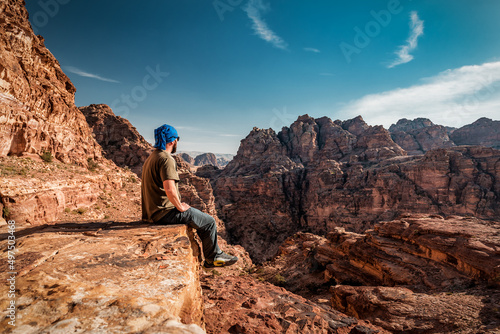 tourist sitting on the rock at the red rocky mountains in jordan photo