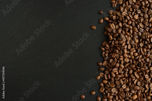 Coffee beans on black stone background. Roasted Coffee beans texture, top view, copy space