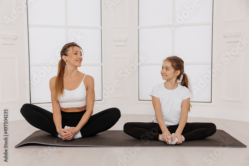 Mother and daughter doing butterfly pose in bright spacious yoga center