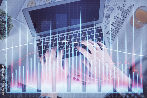 Double exposure of man's hands typing over laptop keyboard and forex chart hologram drawing. Top view. Financial markets concept.