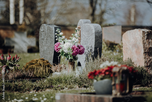 Fotografia grave stone with flowers at graveyard