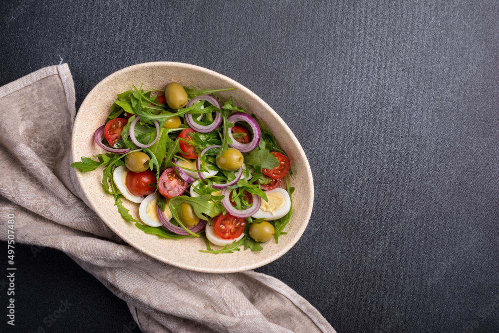 Healthy salad with fresh arugula, cherry tomatoes, quail egg and olives Healthy salad with fresh arugula, cherry tomatoes, quail egg and olives