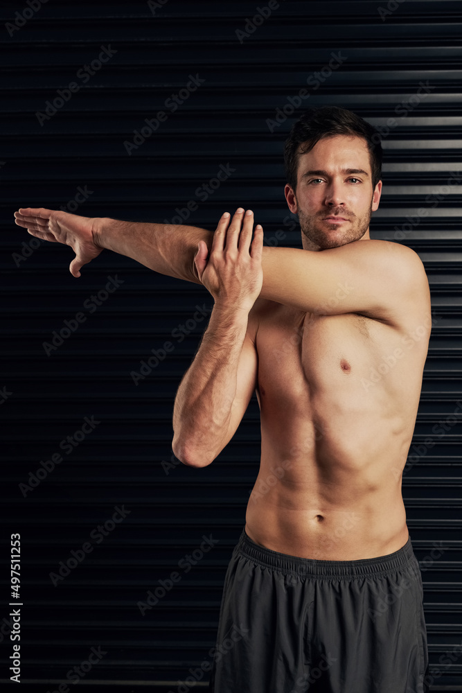 Dont forget to warm up. Studio portrait of a shirtless and well built man warming up against a dark background.