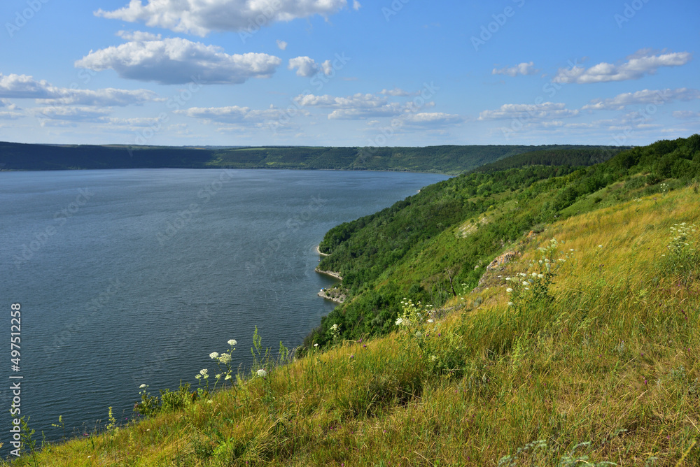 The panoramic landscape of Bakota Bay view. Dniester river, Ukraine. The banks of a large river with small waves on the water. Panoramic river, high banks, green hills. Summer day.