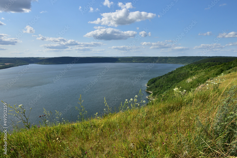 The panoramic landscape of Bakota Bay view. Dniester river, Ukraine. The banks of a large river with small waves on the water. Panoramic river, high banks, green hills. Summer day.