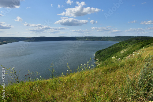 The panoramic landscape of Bakota Bay view. Dniester river, Ukraine. The banks of a large river with small waves on the water. Panoramic river, high banks, green hills. Summer day.