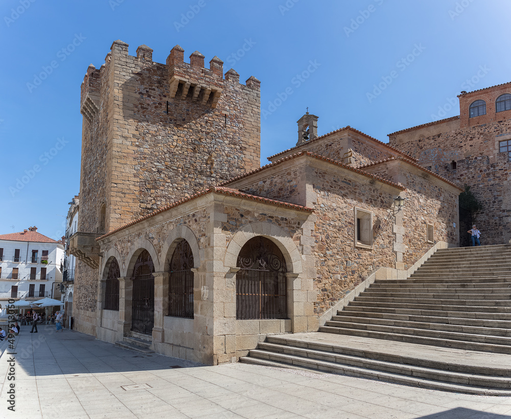 View at the iconic Torre Bujaco, Arco de la Estrella and other heritage buildings on Plaza Mayor in Cáceres city downtown, tourist people strolling, Spain